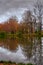 Trees with yellow and red leaves on the banks of the pond in the autumn park are reflected in the water.