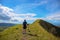 Trekker with backpack on the top of hill on natural mountain landscape. Tourist travels through the mountains. Outdoor activity