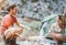 Trekker couple camping in rock mountains with a tent - Climber people cooking and drinking hot tea next to bonfire