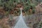 Trekker crossing metal suspension bridge in Nepal, Himalayas