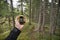 A trekker is finding the right position in the forest via gps in a cloudy autumnal day