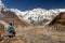 Trekker looking at Annapurna snowcapped mountain summit and its glacier during sunny clear day with blue sky, Himalayas