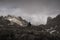 Trekker stands at the edge of a cliff looking at the outstanding peaks