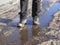 Trekking boots in the muddy spring. The ice melts in the spring, a man walks through puddles on the street, spring weather