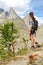 Trekking girl on high mountain trail pointing at peak