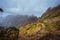 Trekking path along the mountain edge overgrown with verdant grass. Mountain peaks are covered by fog . Xo-Xo Valley