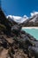 .Trekking path between bushes in the turquoise lagoon of paron and with snowy high mountain peaks in the background