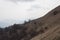 Trekking path crossing slope with dry grass and mountains on background