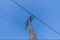 Trellis, pole to support high voltage cables with clear blue skies.