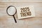 Trend 2025 text message and magnifying glass with space copy on wooden background