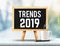 Trends 2019 on blackboard with easel on marble table with sun an