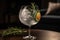 A trendy, artisanal gin and tonic, served in a large, balloon glass with a variety of botanical garnishes, such as cucumber,
