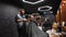 Trendy barber cuts bearded man`s hair with a clipper in barbershop. Men`s hairstyling and hair cutting in salon