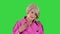 Trendy beautiful senior woman in a pink coat walks in and showing her outfit to camera on a Green Screen, Chroma Key.