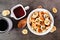 Trendy breakfast pancake cereal with bananas and chocolate chips, top view table scene over a dark background