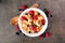 Trendy breakfast pancake cereal with berries, overhead view against dark stone