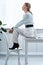 Trendy businesswoman in formal wear sitting on desk