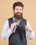 For a trendy casual look. Hipster with long beard and moustache dressing in classic style. Bearded hipster tying a