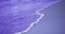 Trendy Color of the year 2022 Very Peri. Seascape. Lilac wave of the sea on the sandy beach close-up. Summer sea background. Lilac