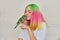 Trendy with colored hair teenager girl with green parrot on hand