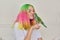 Trendy with colored hair teenager girl with green parrot on hand