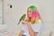 Trendy with colored hair teenager girl with green parrot on hand