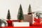 Trendy composition Christmas trees and Santa Hat on podium on red background. New Year concept