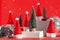 Trendy composition Christmas trees and Santa Hat on podium on red background. New Year concept