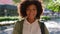 Trendy, cool, and stylish student standing alone. Fashionable woman with afro showing cheerful facial expression in city