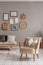 Trendy creme colored armchair in Scandinavian living room interior with gallery of posters on beige wall