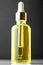 Trendy dropper glass bottle with pipette and yellow liquid on black background