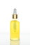 Trendy dropper glass bottle with yellow oil on white background