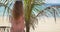 Trendy ethnic lady near palm leaves on beach