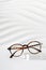 Trendy eyewear photography. Eye glasses creative concept. Classic tortoiseshell frame glasses on a podium on white background.