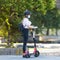 Trendy fashinable teenager girl wearing corona virus protective face mask in public while using rental electric scooters