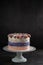 Trendy festive colorful cake on cake stand over dark background.