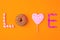 Trendy flat lay lettering. Inscription love by sweets on orange vivid background, isolated