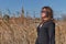 Trendy girl in elegant spring dress in the field with rushes in sunshine ina river close to the sea