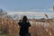 Trendy girl in elegant spring dress in the field with rushes in sunshine ina river close to the sea