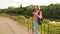 Trendy girl in glasses using smartphone in the European city. She standing outdoors on the bridge. Sunset.