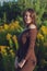 Trendy girl in stylish summer dress feeling free in the field with flowers in sunshine