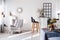 Trendy grey armchair next to two black wooden bar stools in fashionable kitchen and dining room