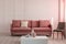 Trendy grey chair next to pastel pink couch