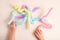 Trendy kids toys pastel colorful pop-tube in baby toddler hands on beige background. Set of forms and colors corrugated