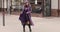 Trendy lady in all violet and purple dancing in the street.