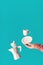 Trendy levitation Flying coffee beans, espresso cup with saucer balancing on index finger of female hand. Ceramic coffee maker