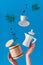 Trendy levitation Flying coffee beans, espresso cup with saucer and wooden storage barrel with lid. Ceramic stove coffee maker