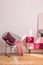 Trendy metal armchair with burgundy pillow and pink blanket next to classy suede covered cabinet, real photo with copy space on