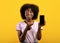 Trendy mobile phone. Excited african american woman holding smartphone with black screen in hand, pointing finger on it