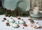 Trendy mousse cake with mirror glaze decorated fir tree, pine cone and Plate with cups on background. Holiday decoration Serving